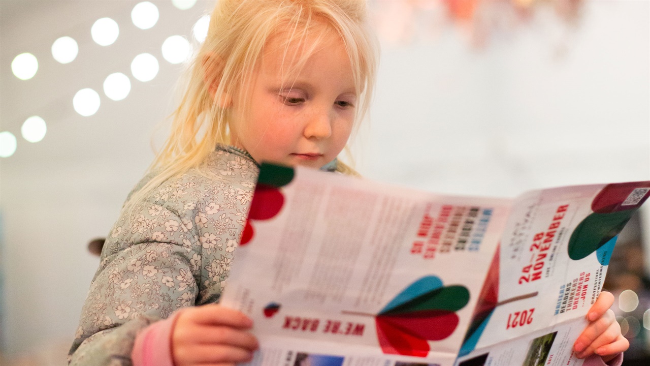 Little girl reading a programme