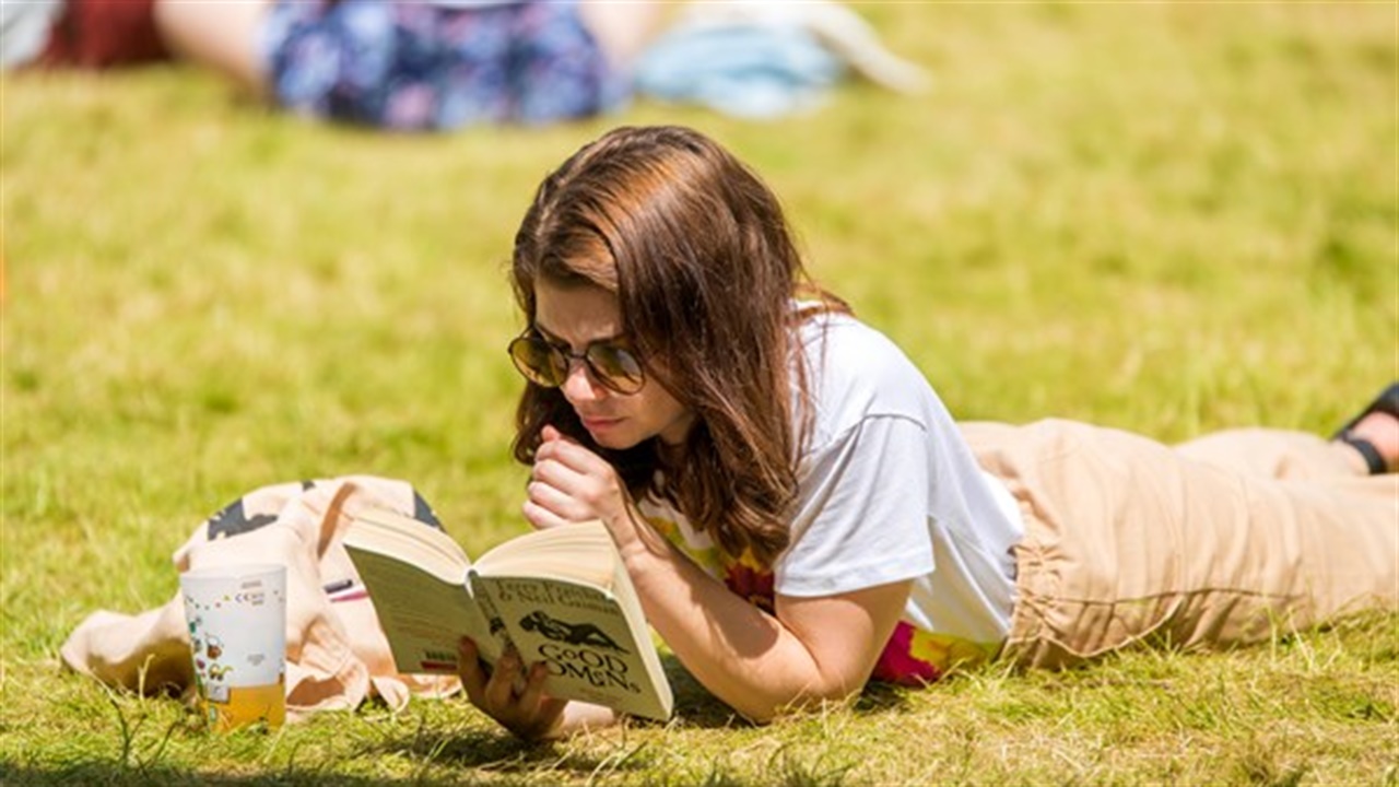 Woman reading a book lying on grass