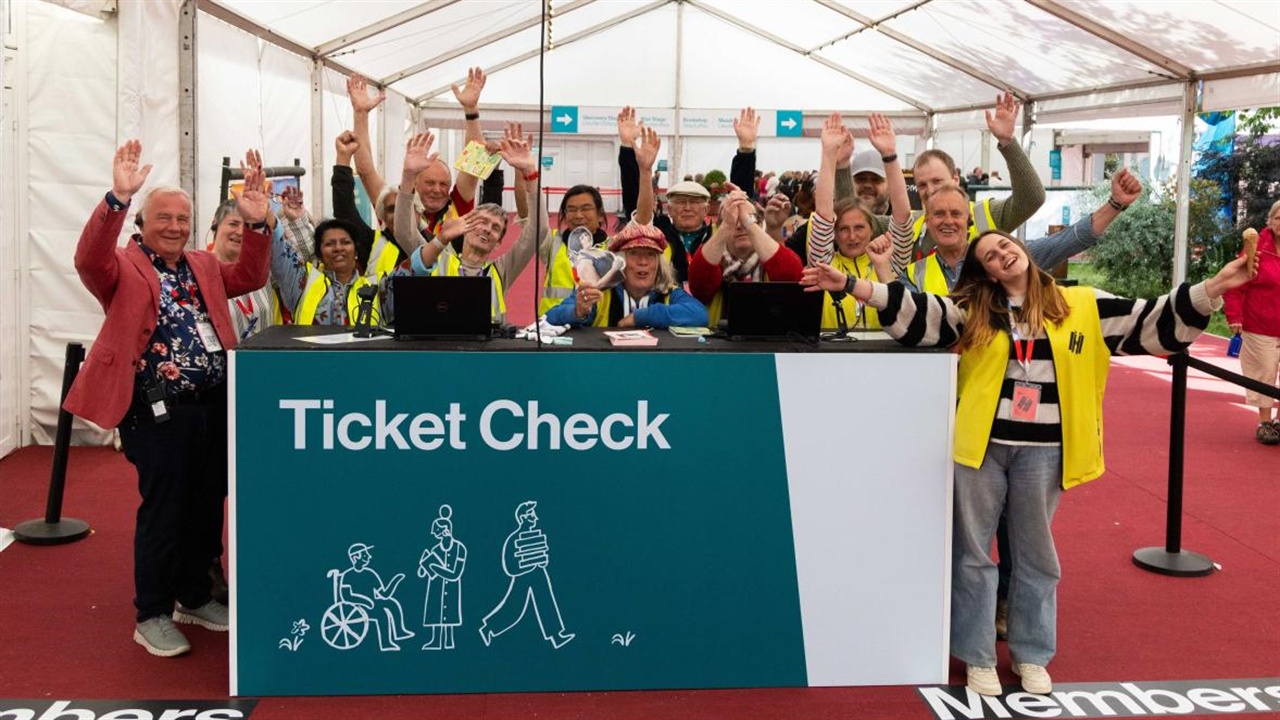 A group of Hay Festival stewards at the ticket check desk waving towards the camera