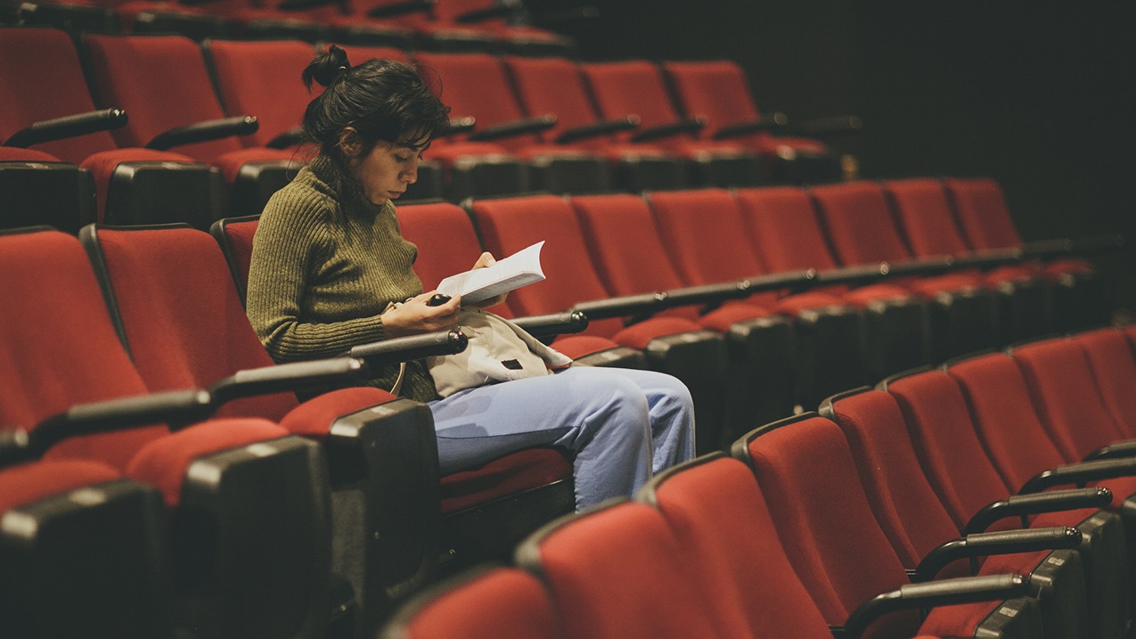 Mujer leyendo en un auditorio vacío
